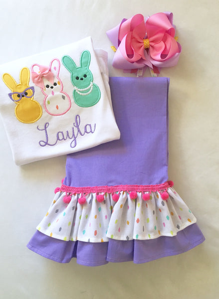 Girls easter outfit with shirt and ruffled pants and easter bow. Shirt embroidered with three decorated bunnies inspired by Peeps! Lavender double ruffle pants finished with a confetti top ruffle and pink pom pom.