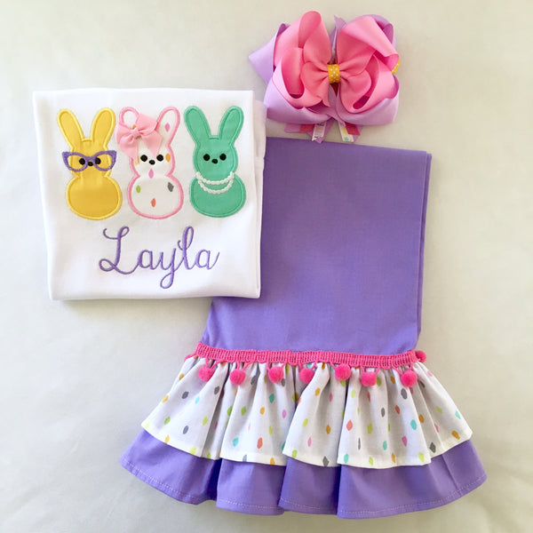 Girls easter outfit with shirt and ruffled pants and easter bow. Shirt embroidered with three decorated bunnies inspired by Peeps! Lavender double ruffle pants finished with a confetti top ruffle and pink pom pom.