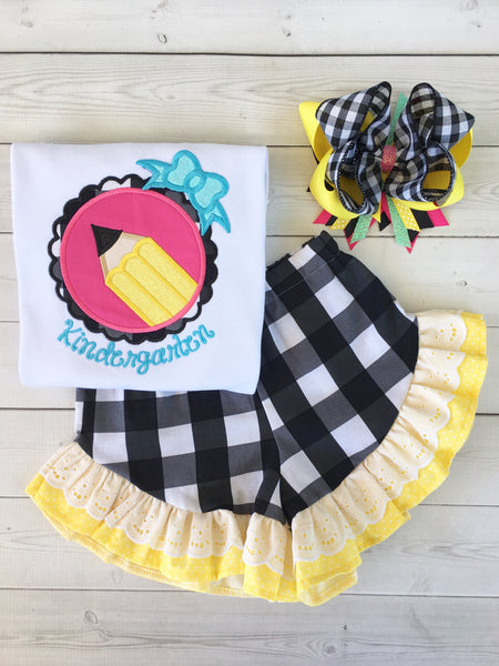 Back to school outfit for girls, embroidered back to school shirt with glitter accents and personalized school year. Yellow pencil in pink fram surrounded by black and white plaid. Black and white plaid shorts with yellow and white lace double ruffle.